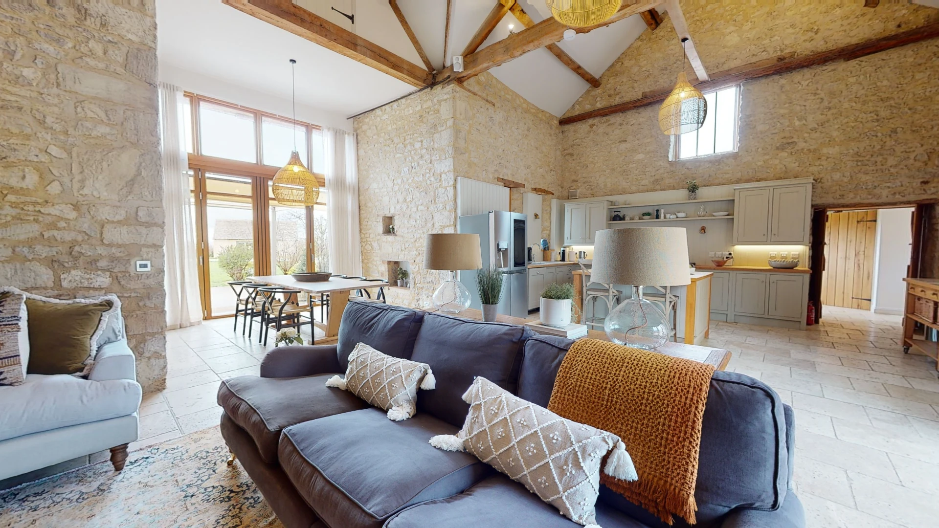 Stone Barn sitting area with a deep grey corner sofa beneath a full-height glazed gable