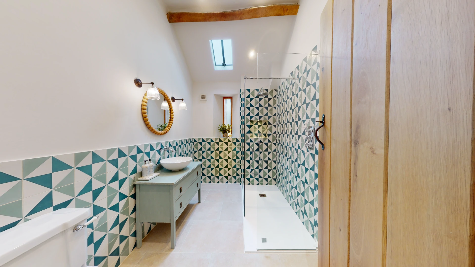 Stone Barn shower room with green and white geometric tiling, a walk-in shower and a brass framed mirror