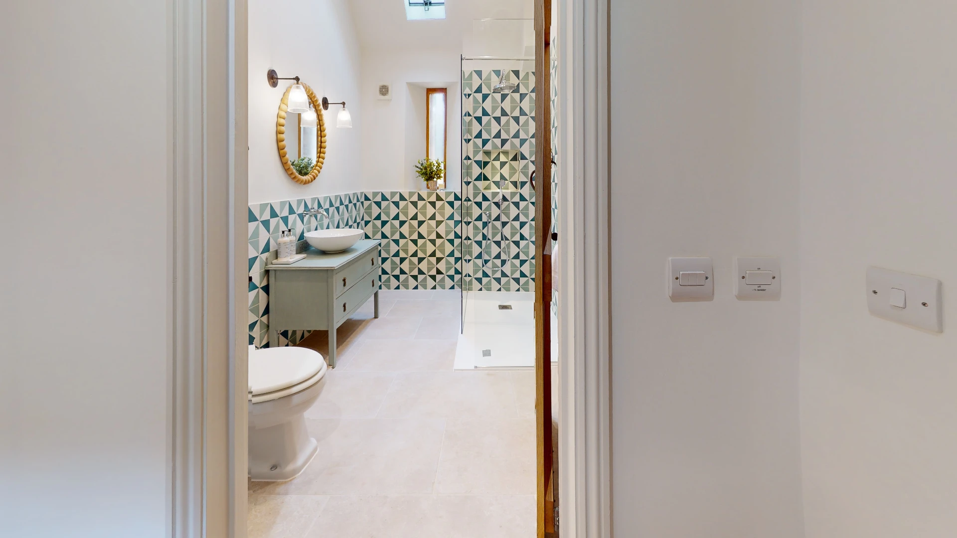 Stone Barn bathroom seen through the doorway, with patterned tiling and a freestanding vanity unit
