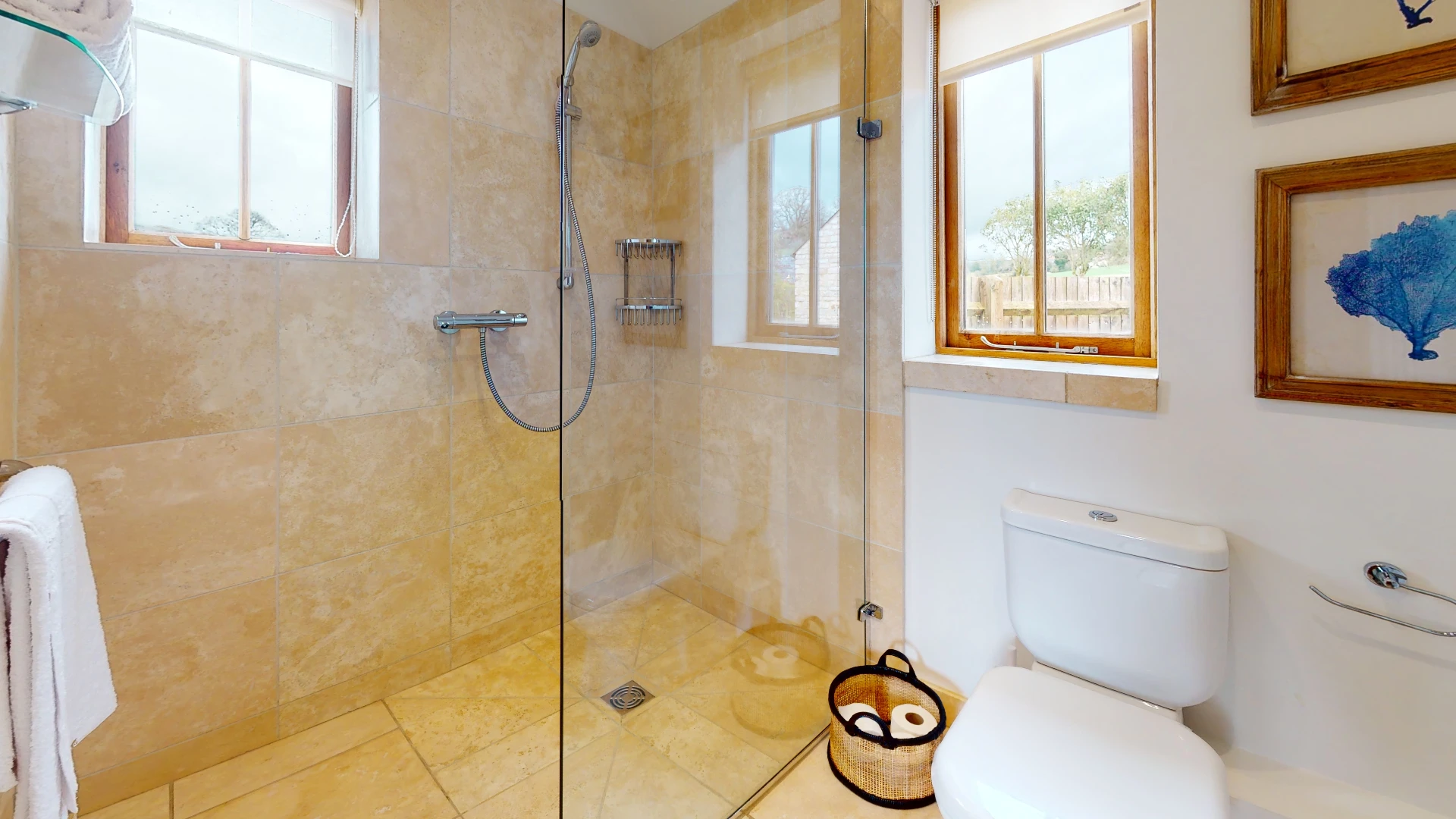 Stone Barn shower room lined in honey-toned stone tiling with a glazed walk-in shower