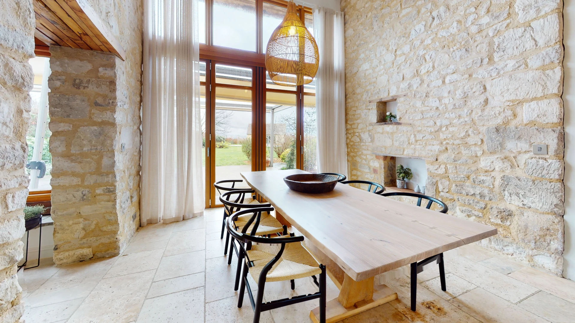 Stone Barn dining room with a long oak table, black metal chairs and an exposed stone chimney breast
